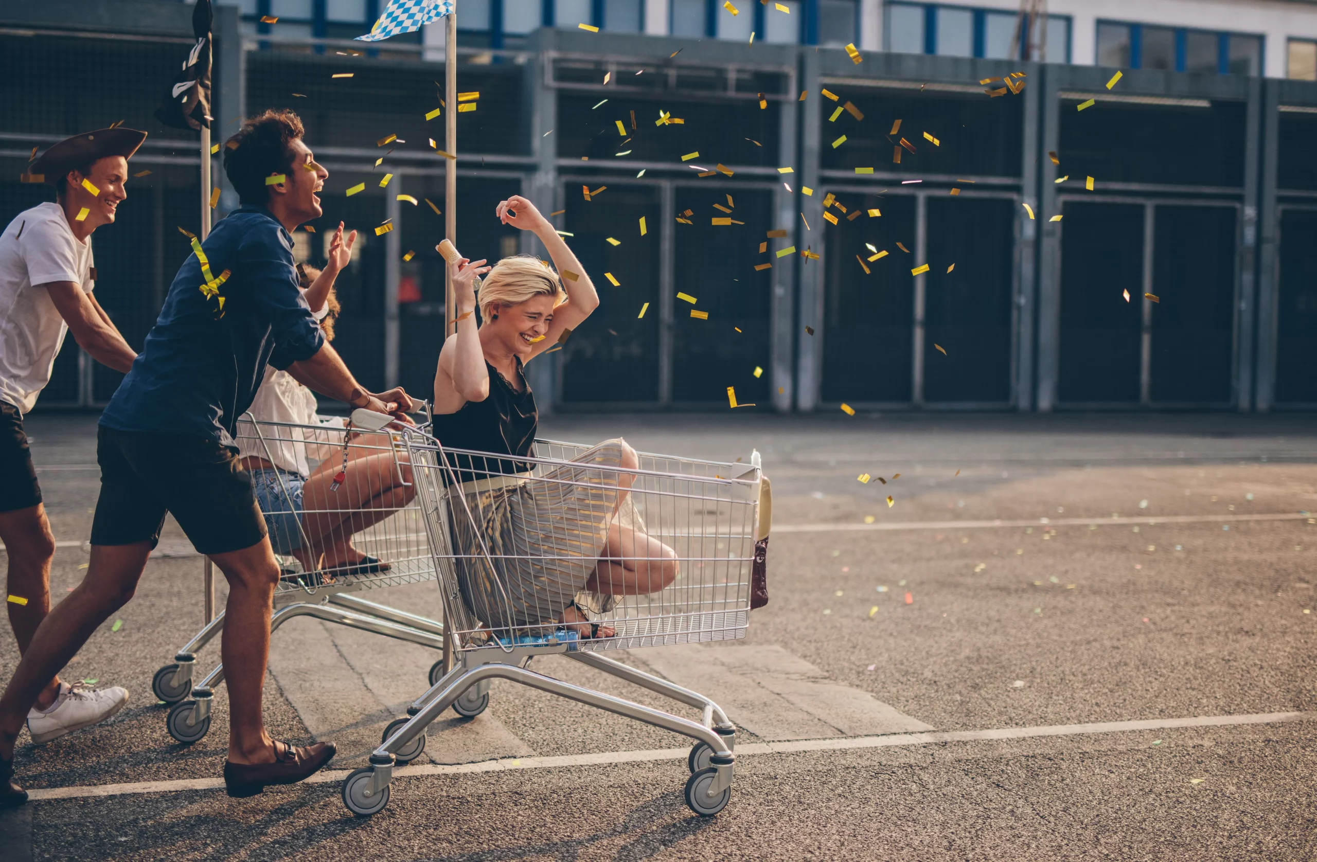 Freunde liefern sich ein Einkaufswagen-Rennen auf einem Parkplatz